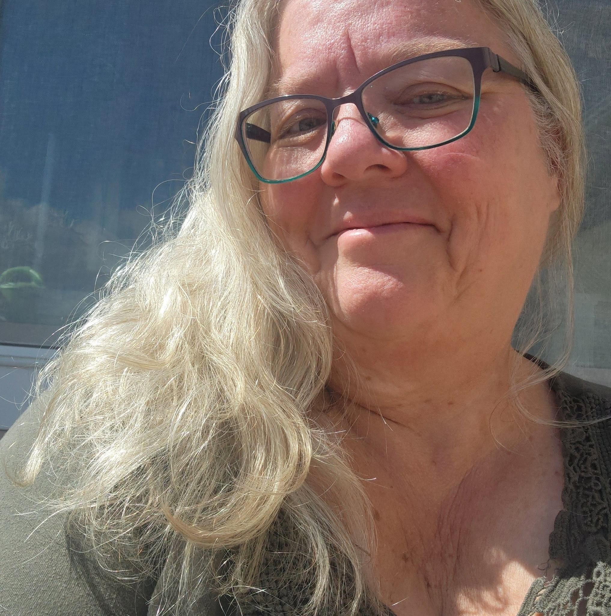 Portrait of Shawn Marie Graybeal-Sellers in her sunlit home study surrounded by books and quilts